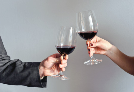 Male and female hands holding glasses with red wineの写真素材