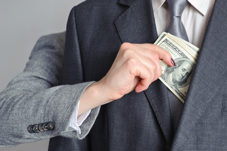 Female hand pulls money from the men of the jacketの写真素材