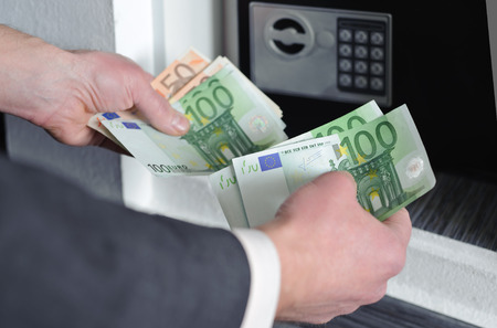 Human hands holding money against a background of safeの写真素材