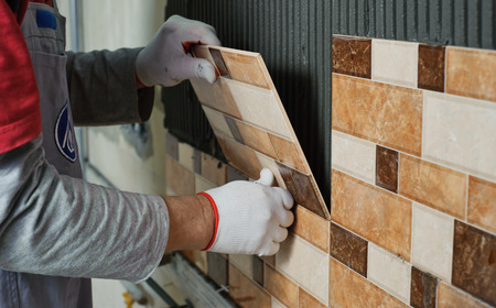 Laying Ceramic Tiles. Tiler placing ceramic wall tile in position over adhesiveの写真素材