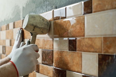 Laying Ceramic Tiles. Tiler knocking on the tiles with a rubber malletの写真素材
