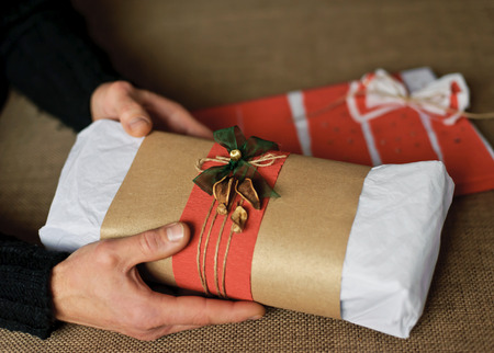 Gift decorated with red ribbon, bow and rope on handsの写真素材