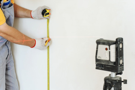 Worker making measurement using laser levels and measuring tape.の写真素材