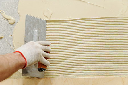Laying plywood on the floor. A worker puts glue for gluing of the plywoodの写真素材