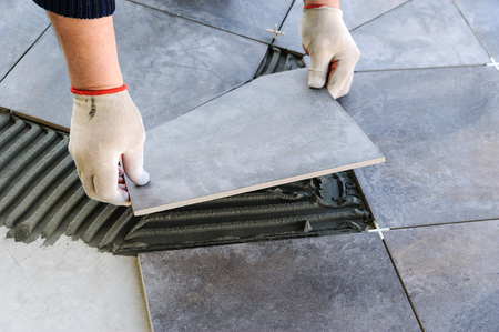 Laying Ceramic Tiles. Worker putting tiles on the balcony.の写真素材