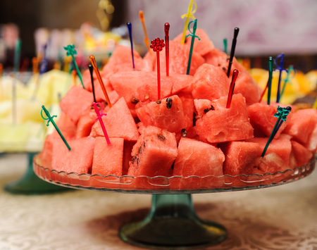 Slices of watermelon is punctured skewers on a trayの写真素材