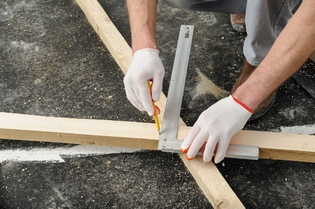 Worker measures off a wooden beam to cut it further.の写真素材