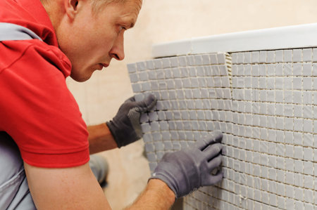 Installation of mosaic tiles. The worker fixes the tile to the base