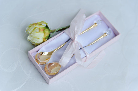 Stylish teaspoons and rosebud on a white tableclothの写真素材