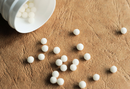 Homeopathic balls scattered from an open container. Closeup.の写真素材