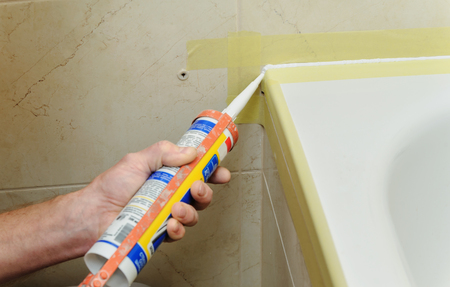Worker puts silicone sealant to caulk the joint between tub and wall.の写真素材
