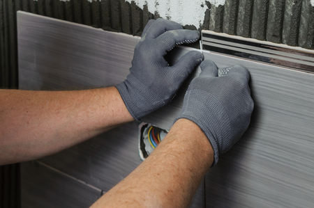 Laying Ceramic Tiles.Tiler aligns seam between the tiles Laying Ceramic Tiles.Tiler aligns seam between the tiles
