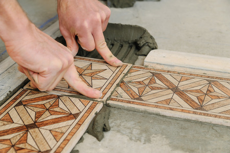Worker putting tiles on the floor. It installs strips.の写真素材
