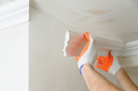 Installation of ceiling moldings. Worker fixes the plastic molding to the ceiling.