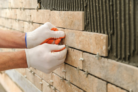 Installing the tiles on the wall. A worker putting tiles in the form of brick. He places the plastic...