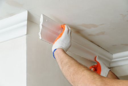 Installation of ceiling moldings. Worker fixes the plastic molding to the ceiling.の写真素材