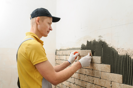 Installing the tiles on the wall. The worker putting tiles in the form of brick.の写真素材