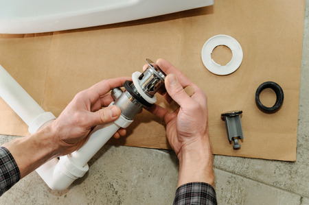Hands man mounted sewer drain with pop-up waste for bidet.の写真素材