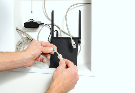 Connecting wi-fi router to the Internet. Human hand holding the cable and connector.