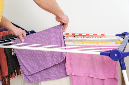A man takes off towels from drying rack clothes.