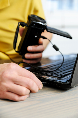 Work at home. Man connects the the camcorder to a laptop.の写真素材