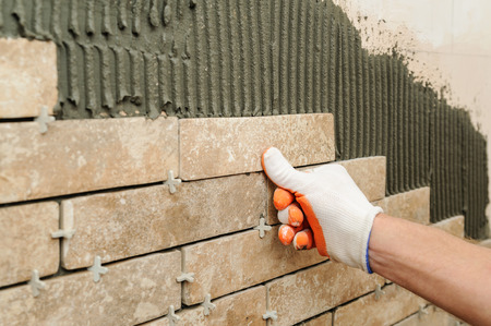 Installing the tiles on the wall. A worker putting tiles in the form of brick.の写真素材