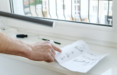 Forefinger of a man's hand directed to instruction for installing roller blind.の写真素材