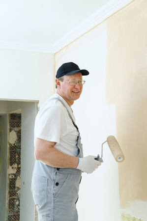 Painter paints a wall in the room. He holds in  hand roller.の写真素材