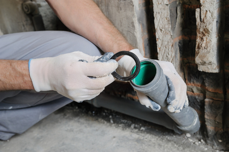 Worker's hands are installing sewer pipes in a kitchen of a apartment.の写真素材