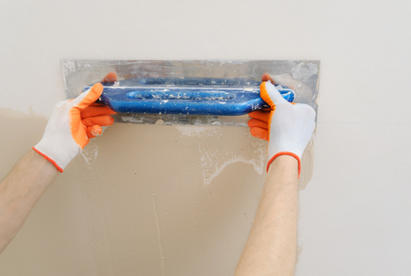 Worker's hands are plastering a wall in a apartment.の写真素材