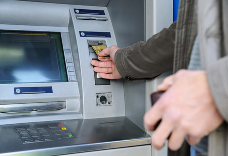 A man is inserting a bank card into an ATM.