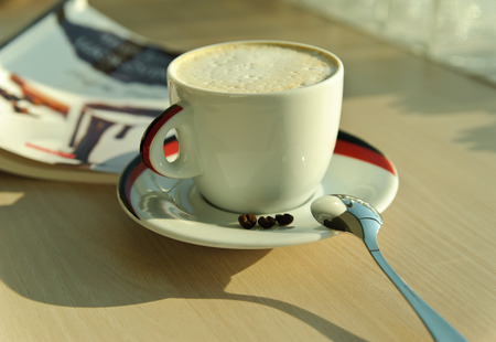 Cup of cappuccino, coffee spoon and three coffee beansの写真素材