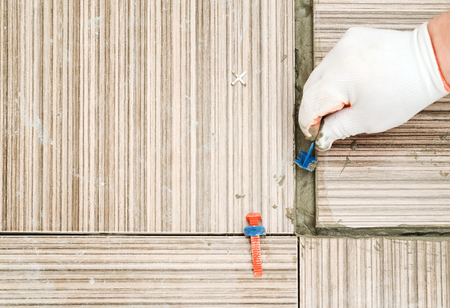 A tile's hand places a plastic clip between the tile. Tile Spacer Leveling System.の写真素材