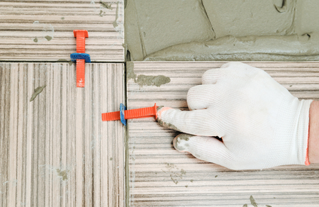 Tiler's hand is using plastic wedges and clips for aligning tiles together.の写真素材