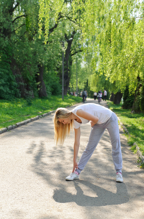 Beautiful girl doing physical exercises on the track in the parkの写真素材