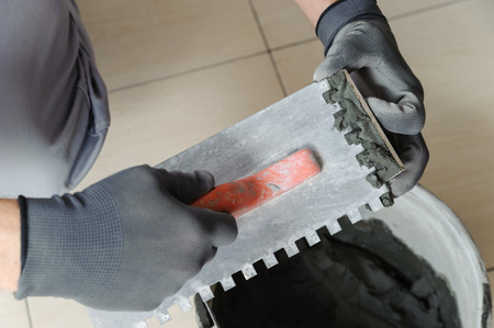 Laying the tiles. Tiler to apply the adhesive on the tile の写真素材