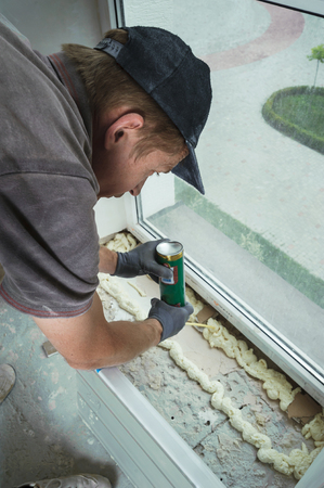 Worker installs plastic sill using polyurethane foamの写真素材