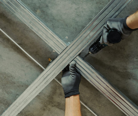 Man assembles profile metal frame for plasterboard ceilingsの写真素材