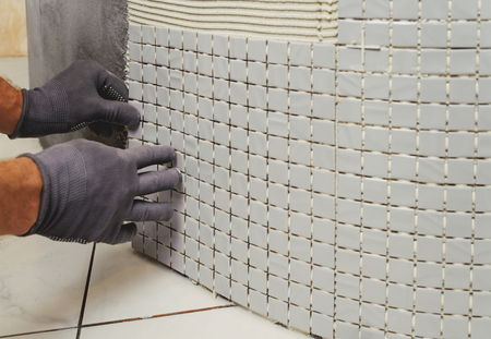 Installation of mosaic tiles. The worker fixes the tile to the baseの写真素材