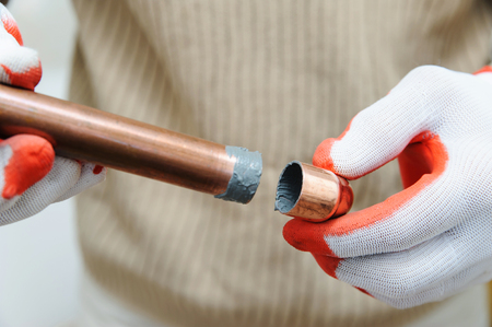 A worker is connecting copper pipes that are ready for soldering.の写真素材
