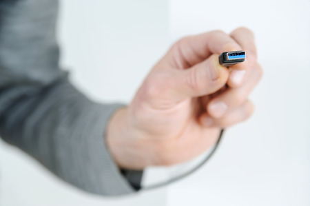 The hand of man is holding the cable plug usb3.の写真素材