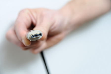 The hand of man is holding the cable plug DisplayPort.の写真素材
