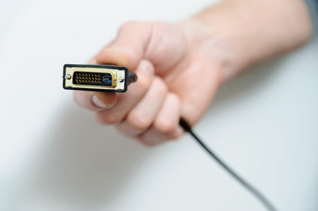 The hand of man is holding the cable plug dvi.の写真素材