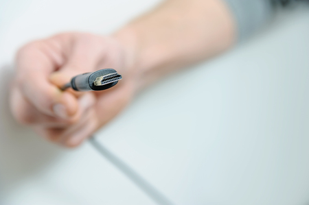 The hand of man is holding the cable plug hdmi.の写真素材