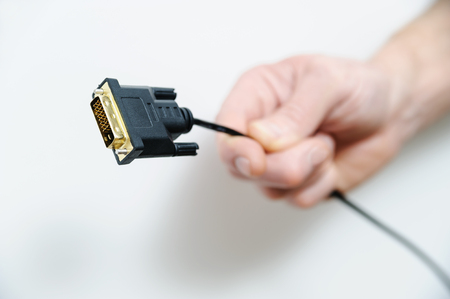 The hand of man is holding the cable plug dvi.の写真素材