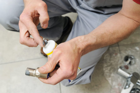 Plumber putting a paste sealant on the thread pipe.