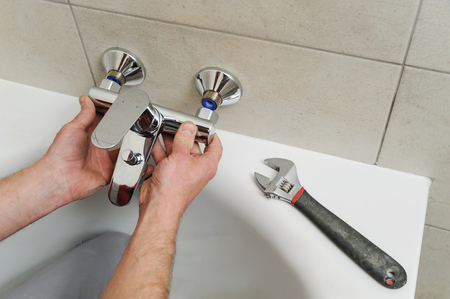 Plumber fixing bath faucet with an adjustable wrench.の写真素材