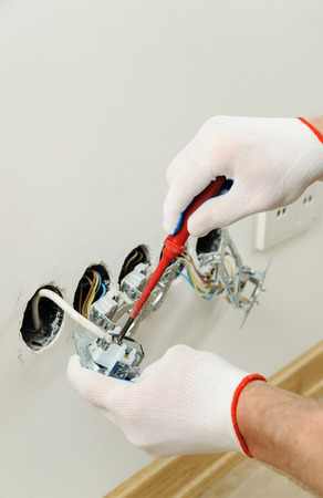 Worker installs a TV wall socket using a screwdriver.の写真素材