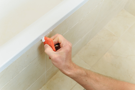 Worker smoothing silicone sealant between the bath and the wall using a spatula.の写真素材