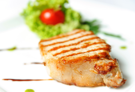 Grilled steak meat with vegetables on a white plateの写真素材